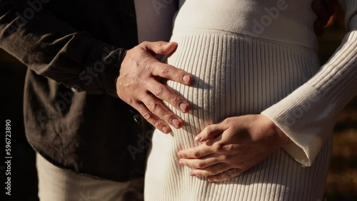 Family day. Stylish unrecognisable marriage pregnant couple waiting for baby. Man is hugging and touching woman belly outdoors. World IVF Day. Pregnancy, parenthood, motherhood, love, family concept