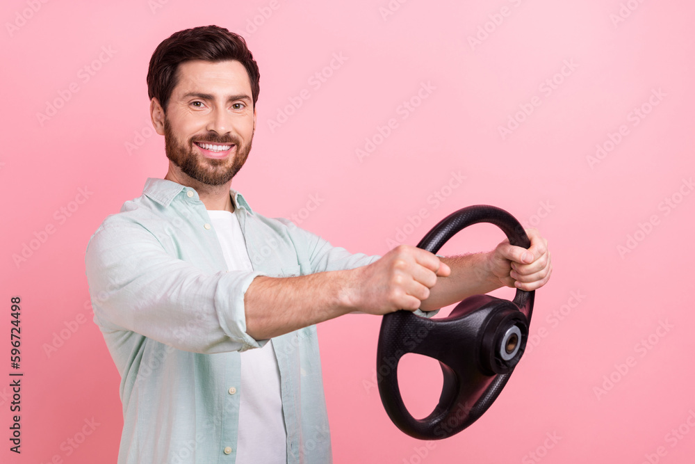 Photo portrait of handsome young guy hold steering wheel rudder cheerful driver wear trendy blue clothes isolated on pink color background Photo portrait of handsome young guy hold steering wheel rudder cheerful driver wear trendy blue clothes isolated on pink color background