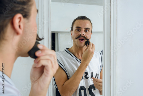 young gender non-binary person, looking in the mirror while putting on makeup, focus on the background