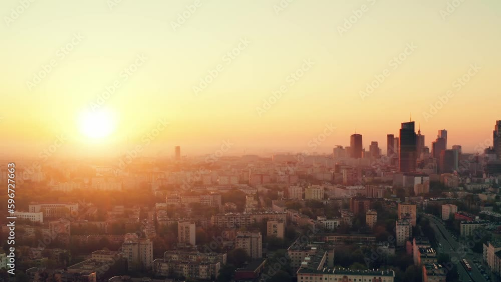 Establishing aerial panoramic view Warsaw city. Cinematic drone shot cityscape downtown skyline, high rise skyscrapers modern architecture buildings on horizon lit with orange sunrise or sunset light Establishing aerial panoramic view Warsaw city. Cinematic drone shot cityscape downtown skyline, high rise skyscrapers modern architecture buildings on horizon lit with orange sunrise or sunset light