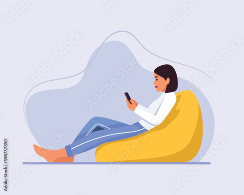  light-skinned girl with short hair sits on a bean bag chair with a phone