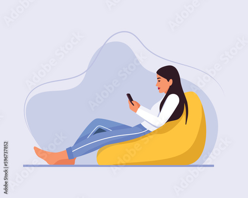  light-skinned girl with long hair sits on a bean bag chair with a phone