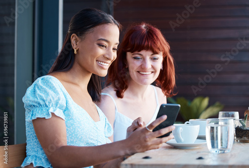 Look at this new app. Shot of two young female friends using a phone together at a cafe.