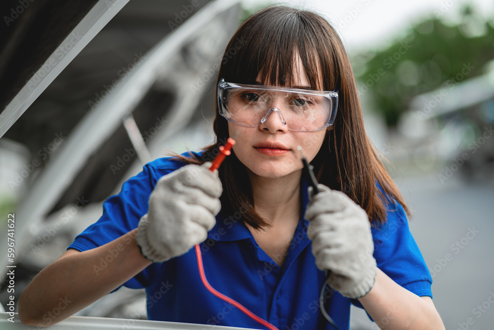 An expert female mechanic and check the car battery with a jumper cable