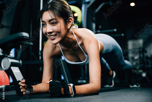 Strong female athlete using a stability ball to add difficulty to her plank exercise and build a powerful core for better overall body shape, exercise in dark gym background