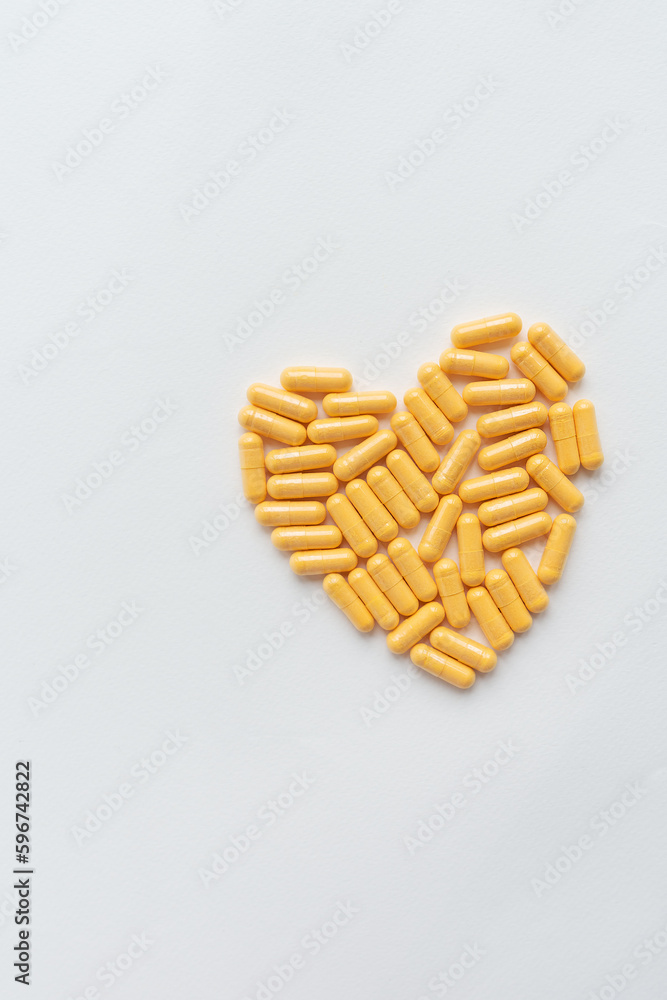 Yellow pills in the shape of a heart, health and heart problems. The concept of medicine and healthcare. Place for an inscription, vertical photo. Yellow pills in the shape of a heart, health and heart problems. The concept of medicine and healthcare. Place for an inscription, vertical photo.