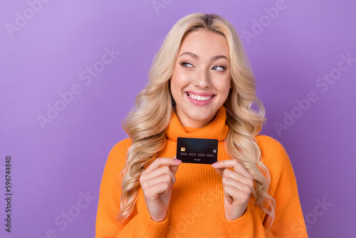 Portrait of gorgeous positive lady beaming smile hands hold debit plastic card look empty space isolated on purple color background