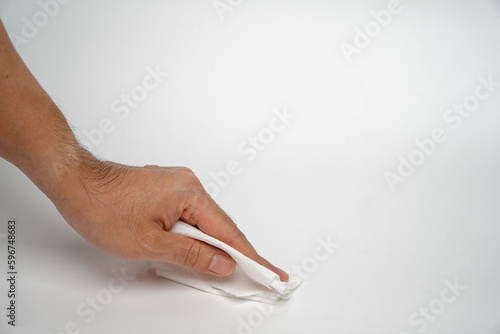 Table cleaning concept.Man's hand is using a tissue paper to clean the white table.