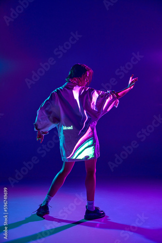 Portrait of sensual beautiful woman dancing with emotion with inscription of neon glow on body over violet background. Turn off the mind © Lustre
