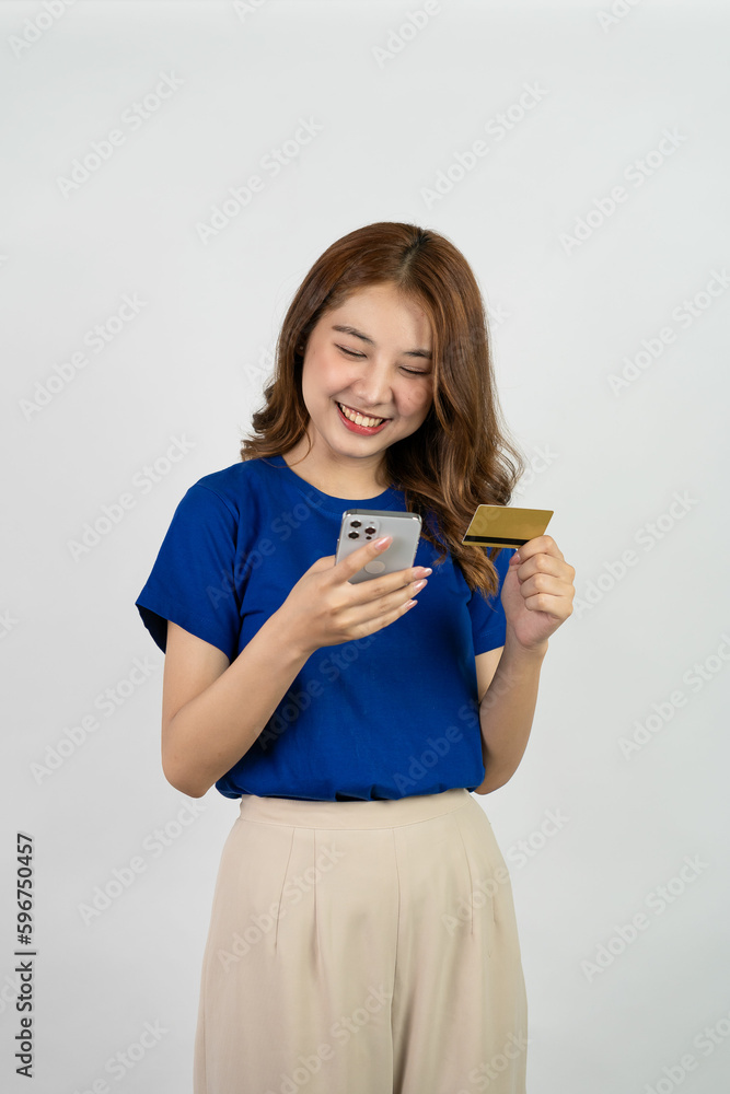 
Cropped view of beautiful asian woman standing holding credit card and smart phone to pay online shopping Attractive woman inserting credit card serial number to pay on internet