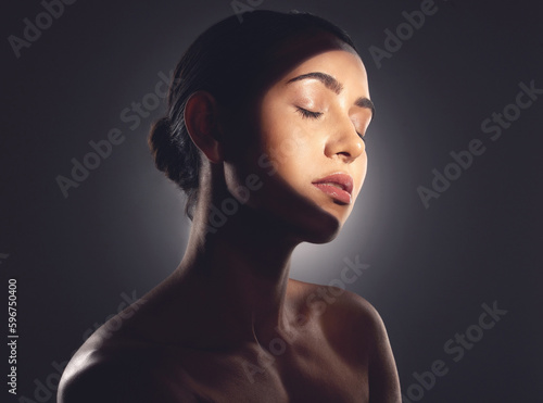 Beauty is the light in the heart. Studio shot of a beautiful young woman posing with light beam against her face.