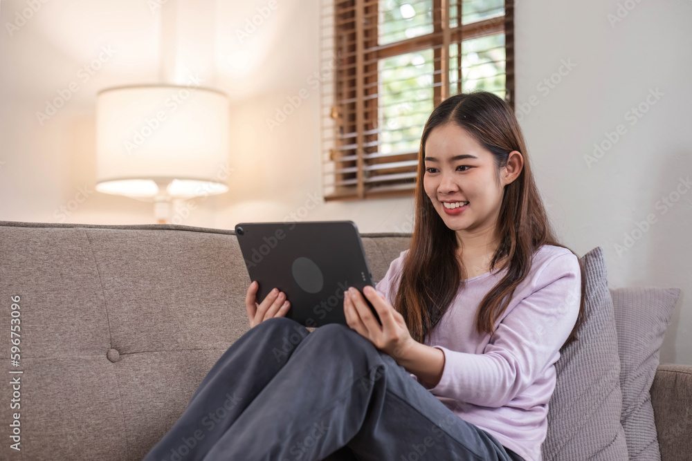 beautiful asian young woman wear casual sit on couch using computer laptop entertain with social media relax smile and laughing.Freelance woman working online sale marketing. Shopping online at home beautiful asian young woman wear casual sit on couch using computer laptop entertain with social media relax smile and laughing.Freelance woman working online sale marketing. Shopping online at home