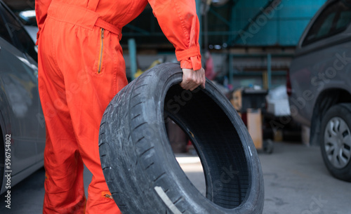 A car mechanic inspects the condition of a car tire before placing it on a vehicle. © Wosunan