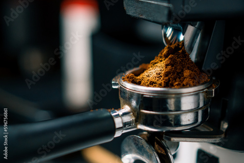 Fotografie Professional barista worker use grinder machine to grind fresh coffee beans for