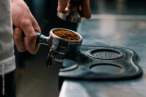 Tableau sur toile A professional barista in a coffee shop prepares ground coffee by tamping fresh