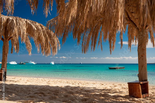 Mahmya Island, Rotes Meer, Ägypten mit Schwimminsel und Booten. Wolkenbild und Palmenwedeln mit blauem Himmel.  photo