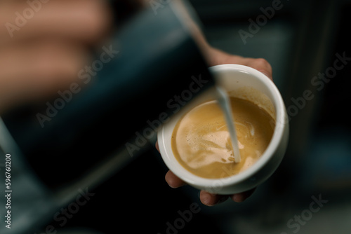 Barista making latte art in a cafe Male hands pouring steam of milk into a cup of Cappuccino with a pattern