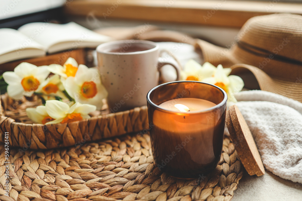 Cozy spring composition, burning candle, daffodils and hat Cozy spring composition, burning candle, daffodils and hat