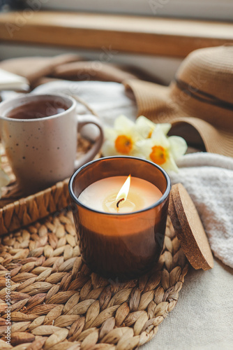 Cozy spring composition, burning candle, daffodils and hat