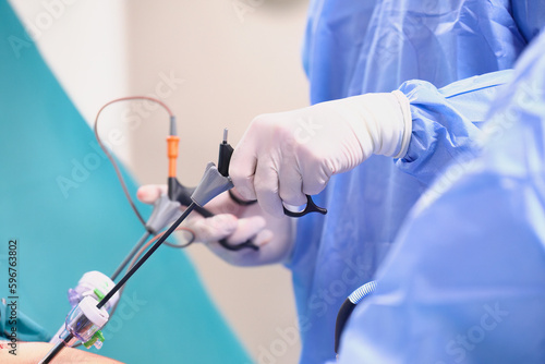 Operacja laparoskopowa na sali operacyjnej w szpitalu. Dłonie chirurga w sterylnych rękawiczkach trzymają narzędzia endoskopowe. Asysta instrumentariuszki. © Tomasz