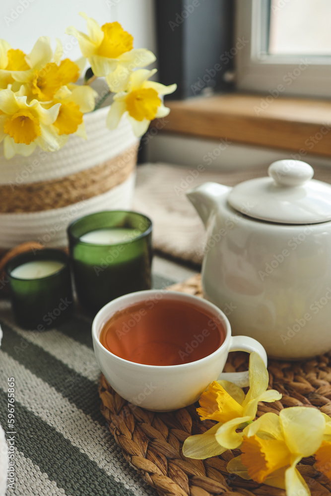 Cup of tea, candles, basket with daffodils, spring aesthetic photo