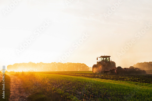 a tractor in a field plows the ground at dawn, sowing grain. High quality photo photo