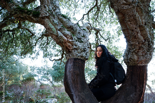ragazza mora vestita di nero è immersa nella natura vicino a un albero secolare
