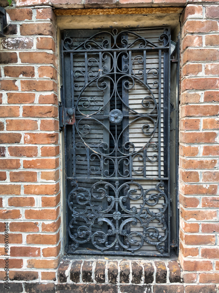 antique iron security gate over a window set in a red brick building