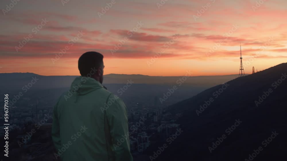 The guy after morning run standing and calm down with a great sunrise view . The guy after morning run standing and calm down with a great sunrise view .