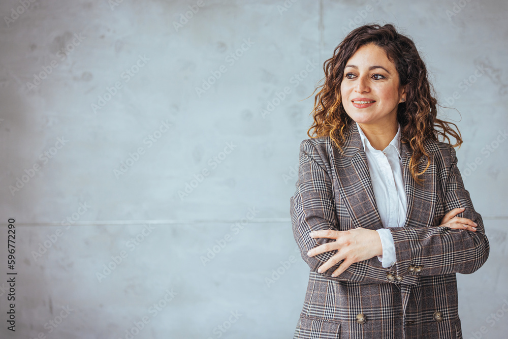 Portrait of young smiling woman looking at camera with crossed arms. Happy girl standing in creative office. Successful businesswoman standing in office with copy space. Portrait of young smiling woman looking at camera with crossed arms. Happy girl standing in creative office. Successful businesswoman standing in office with copy space.