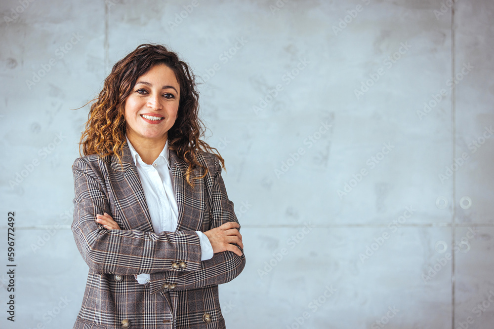Successful businesswoman standing in creative office and looking at camera. Young latin woman entrepreneur in a coworking space smiling. Portrait of beautiful business woman standing Successful businesswoman standing in creative office and looking at camera. Young latin woman entrepreneur in a coworking space smiling. Portrait of beautiful business woman standing