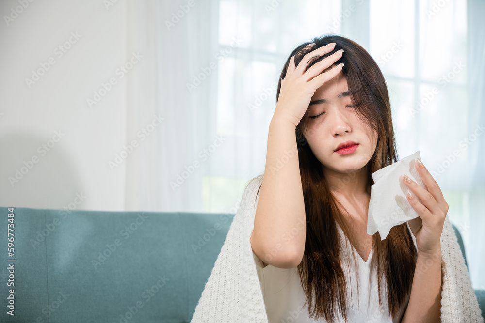 Asian young woman she sick blowing nose sneezing in tissue at home, fever caught cold, Sick female sitting under blanket on sofa and sneeze with tissue paper in living room, medicine healthcare Asian young woman she sick blowing nose sneezing in tissue at home, fever caught cold, Sick female sitting under blanket on sofa and sneeze with tissue paper in living room, medicine healthcare