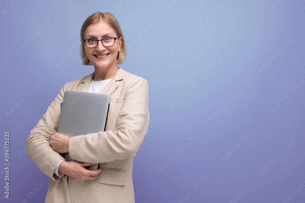 middle-aged mature woman in jacket masters new technique using laptop on studio background with copy space middle-aged mature woman in jacket masters new technique using laptop on studio background with copy space