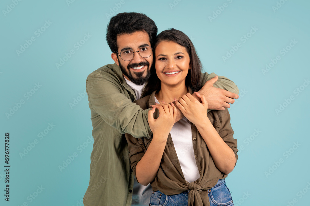 Fototapeta premium Beautiful young indian couple posing on blue studio background