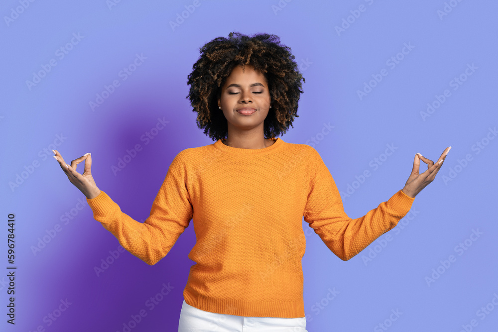 Peaceful relaxed black woman meditating on purple studio background Peaceful relaxed black woman meditating on purple studio background