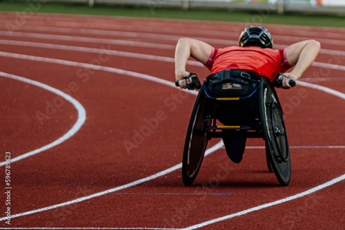 rear view male athlete in racing wheelchair riding on red track stadium, summer para athletics championships