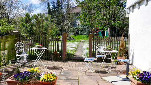 Wunderschöne Gartenterrasse mit Tischen und Stühlen im Frühling photo