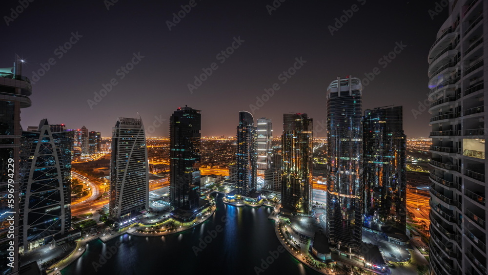 Tall residential buildings at JLT aerial all night timelapse, part of the Dubai multi commodities centre mixed-use district.