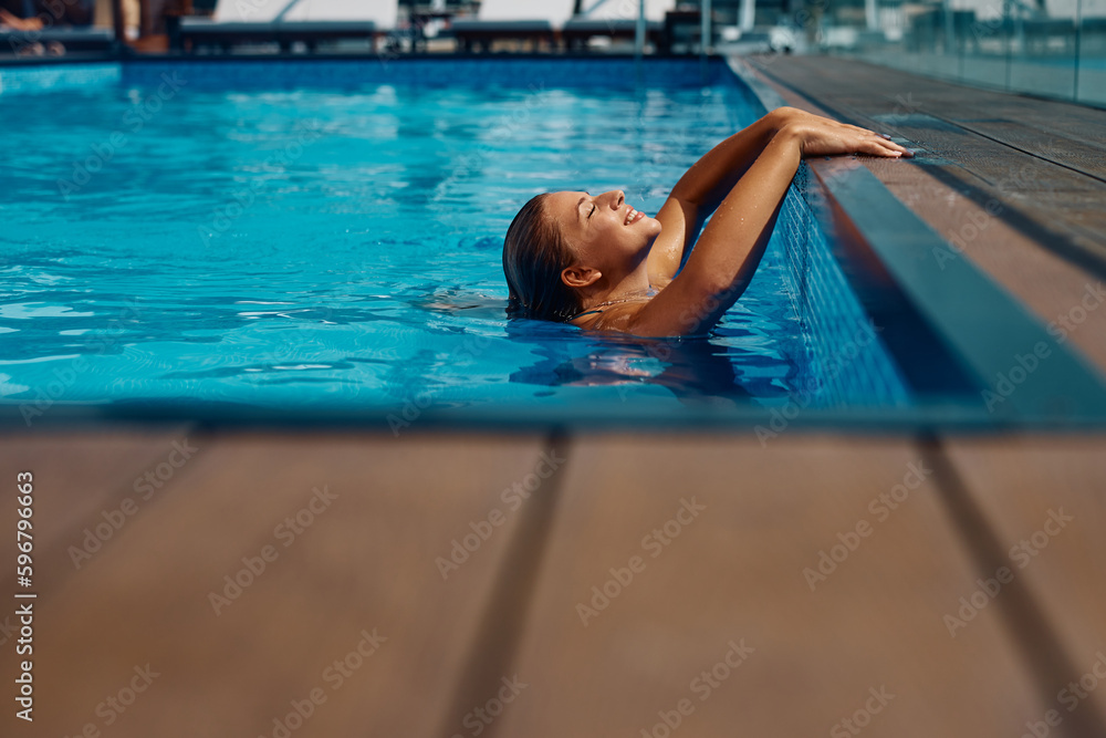 Happy woman enjoys in water at swimming pool during summer day.