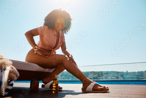 Happy black woman using suntan lotion while spending summer day at swimming pool.