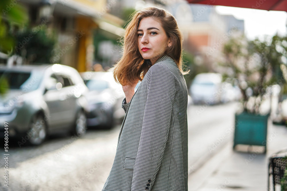 A beautiful young girl in a gray jacket is standing on a city street. A beautiful young girl in a gray jacket is standing on a city street.