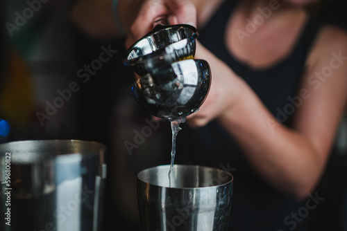Bartender squeezing a lemon with a hand juicer into a shaker to make a cocktail