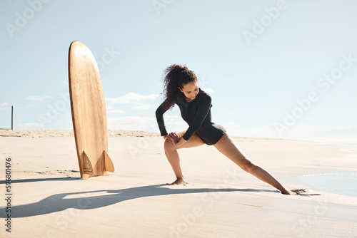 Surfing is attitude dancing. Shot of a young woman stretching on the beach.