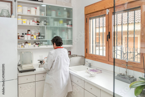 Mature woman in medical uniform pouring drug to volumetric glassware photo