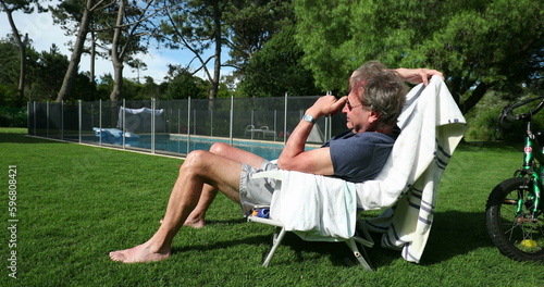 Older man resting sitted outside in home garden. Senior person in outdoor backyard