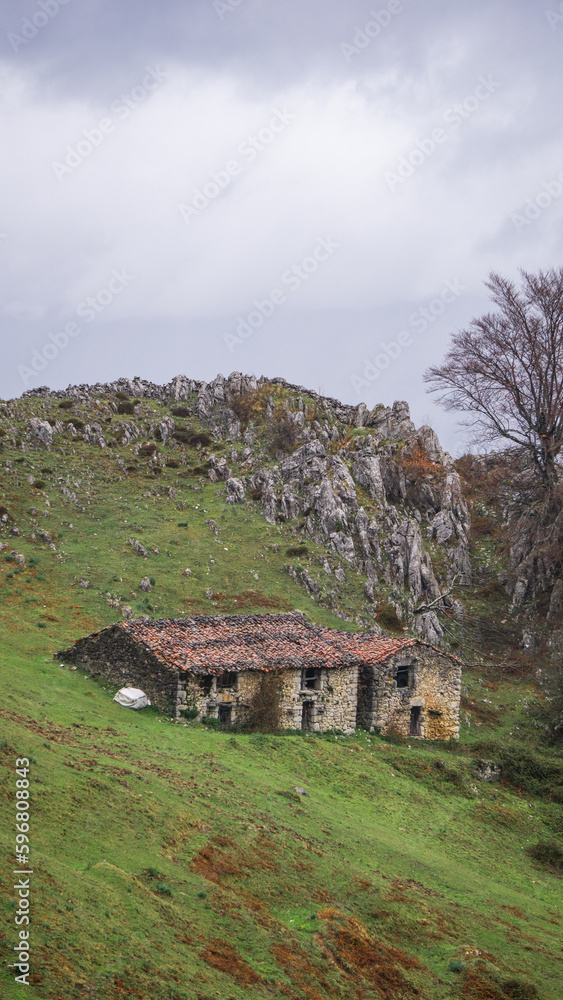 Mountain landscape in a cloudy day with an old house on the green grass Mountain landscape in a cloudy day with an old house on the green grass