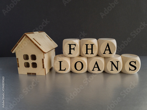 FHA federal housing administration loans symbol. Concept words 'FHA federal housing administration loans' on wooden cubes on a beautiful blak background. Model of house. Business and FHA loans concept photo