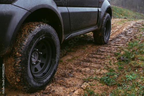 An off-road vehicle with tires for all types of surfaces. Dirt and clay  country road. The mud stuck to the tread. Selective focus. Steel discs