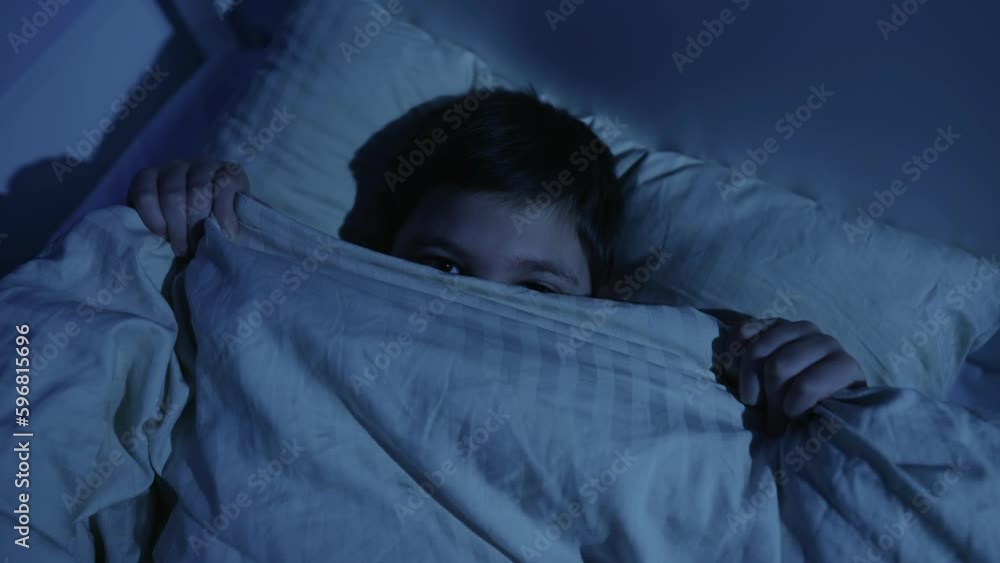 Boy covers himself with a blanket for fear at night Boy covers himself with a blanket for fear at night