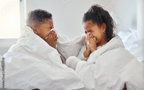 Tis the season to be snotty. Shot of a brother and sister blowing their nose in bed.